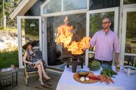 Man in Pink Dress Shirt Sitting on Chair in Front of Fire
