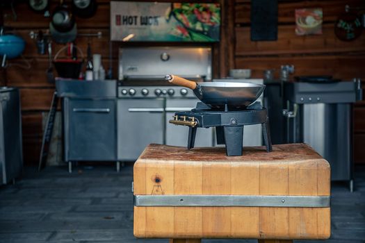 Stainless steel wok on a gas stove in a modern outdoor kitchen setting, emphasizing gourmet cooking.