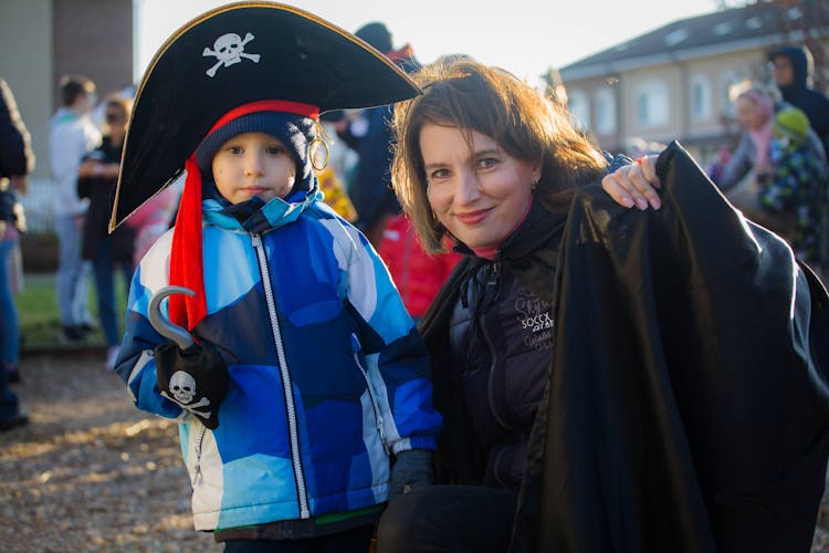 Photograph Of A Kid In A Pirate Costume Beside Her Mother In A Black Jacket