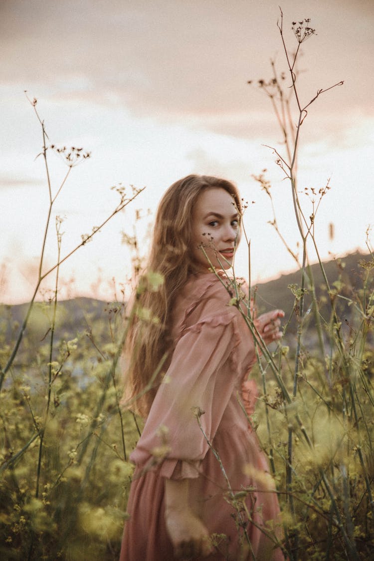 A Woman With Long Hair Running On Grass Field With Wild Flowers