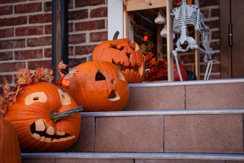 ハロウィンの装飾としてスケルトンがある屋外の階段の上に置かれた3つの彫刻されたカボチャ。