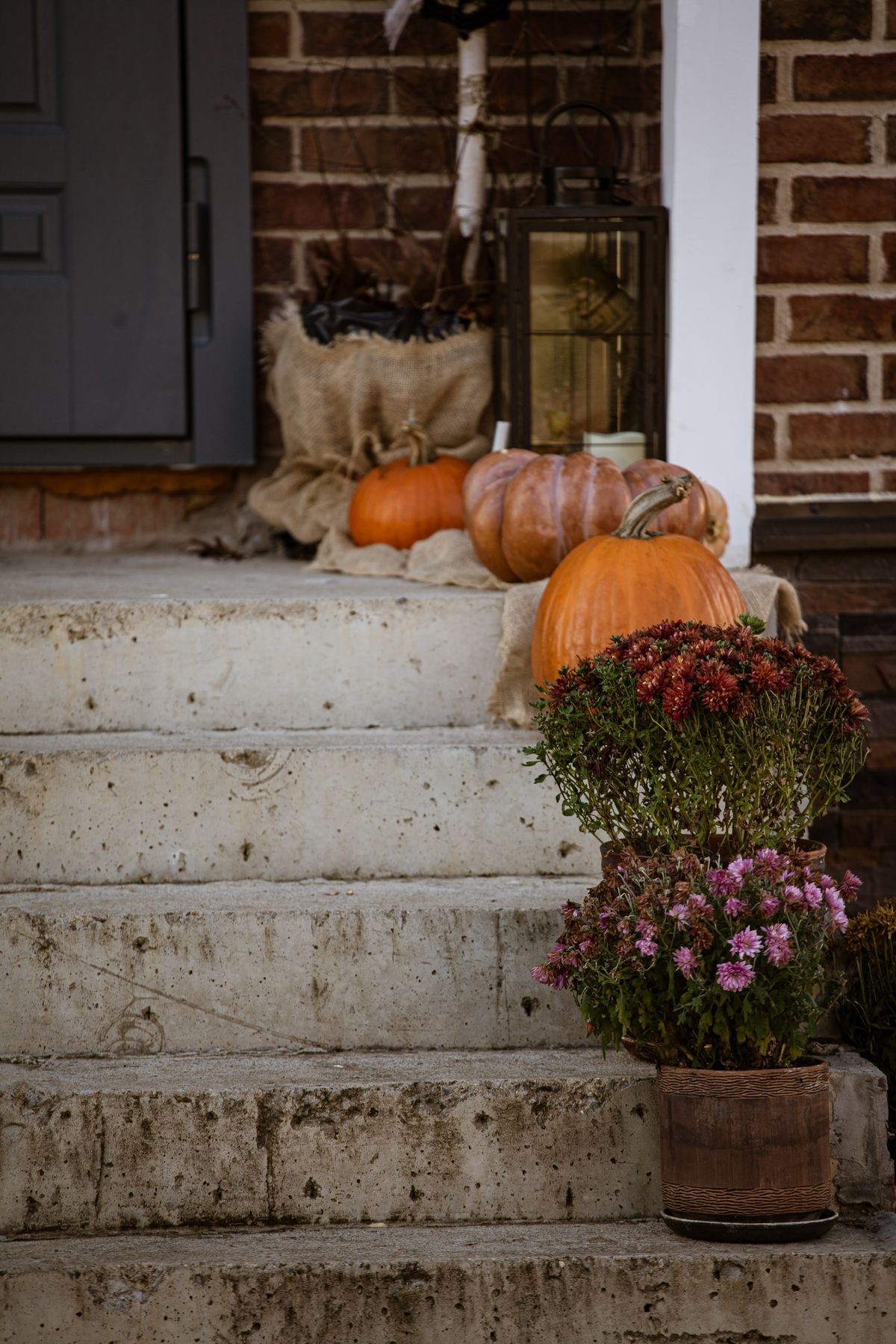 Fall entryway with pumpkins and flowers on concrete steps
