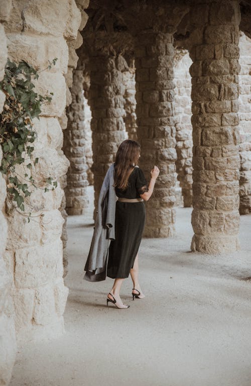 Elegant Woman Walking Toward Stone Columns