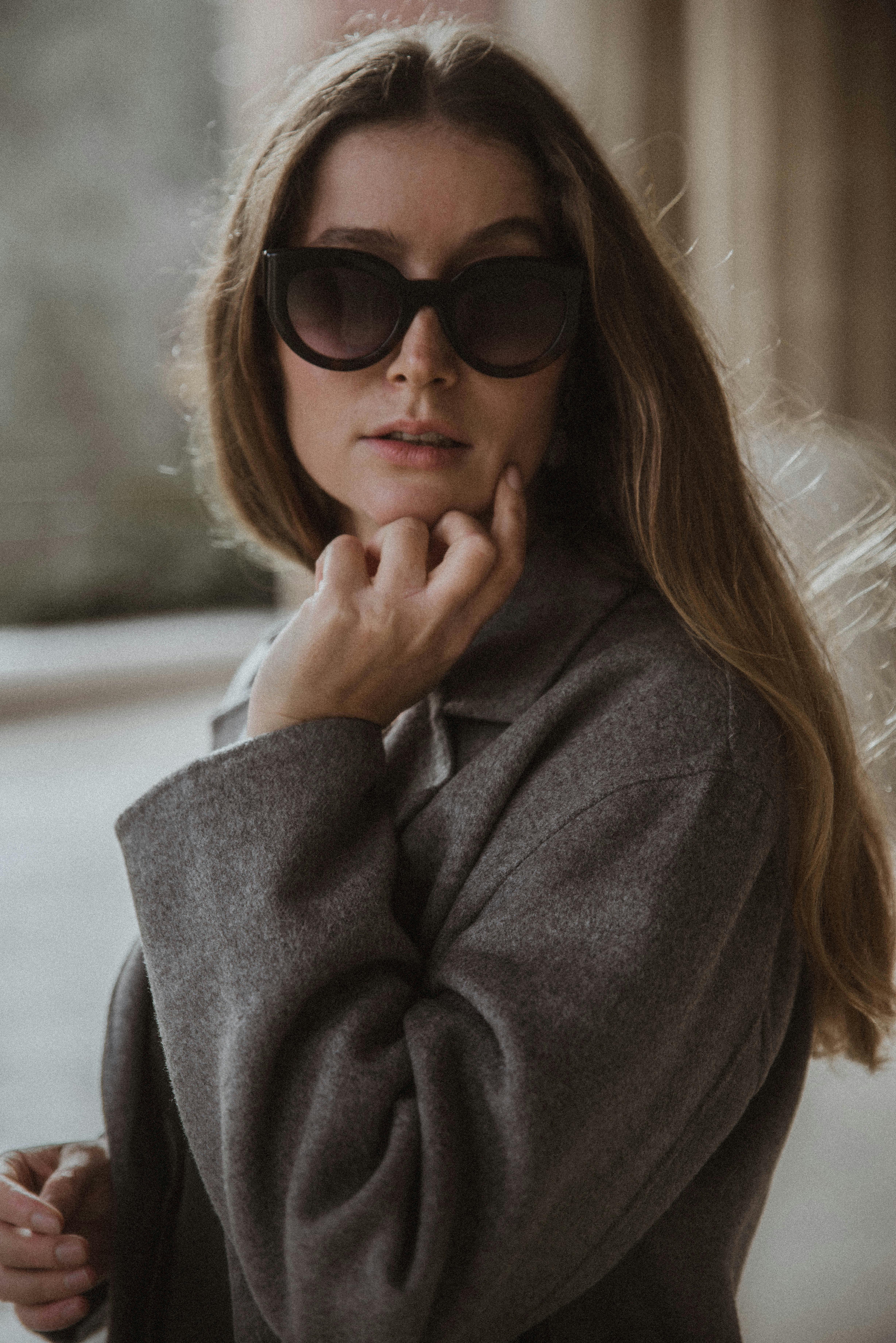 Chic fashion portrait of a woman in sunglasses and coat, exuding elegance.