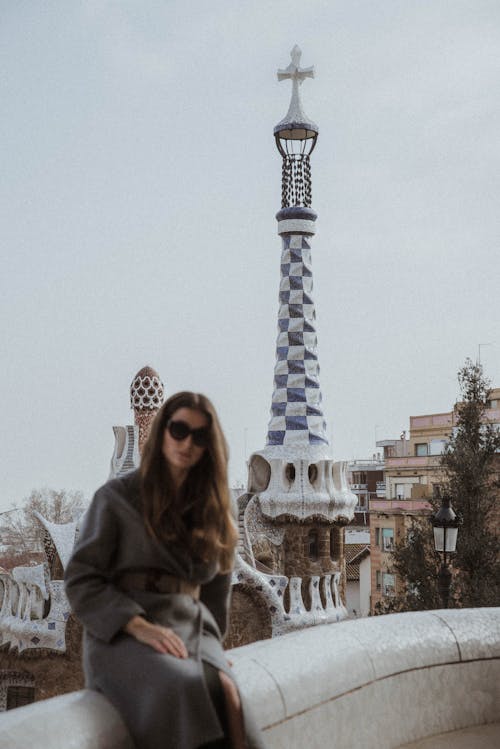 Woman Sitting on Wall with Church Tower behind