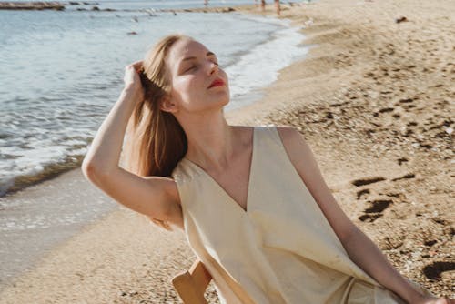 A Woman Sitting on a Wooden Chair on the Shore