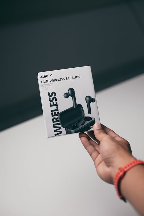 Free Photo of a Person's Hand Holding a White Box of Wireless Earbuds Stock Photo
