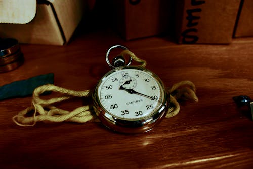 White Pocket Watch With Gold-colored Frame on Brown Wooden Board