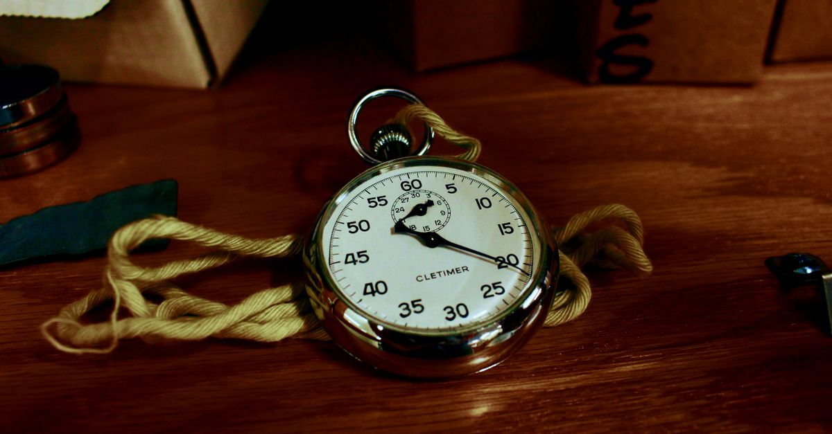 Close-up of an analog stopwatch resting on a wooden surface
