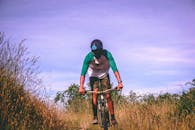 在新西兰尼尔森，一名戴着头盔、穿着休闲装的山地自行车手正穿过一条绿草如茵的小路