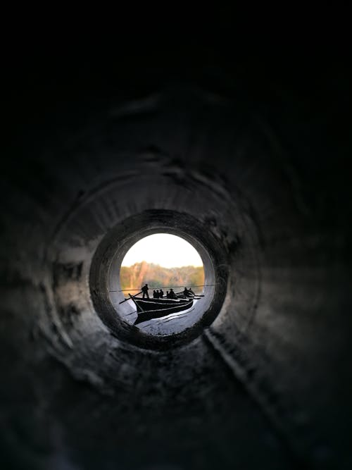 Free People Riding Canoe Boat View from Inside Pipe Stock Photo