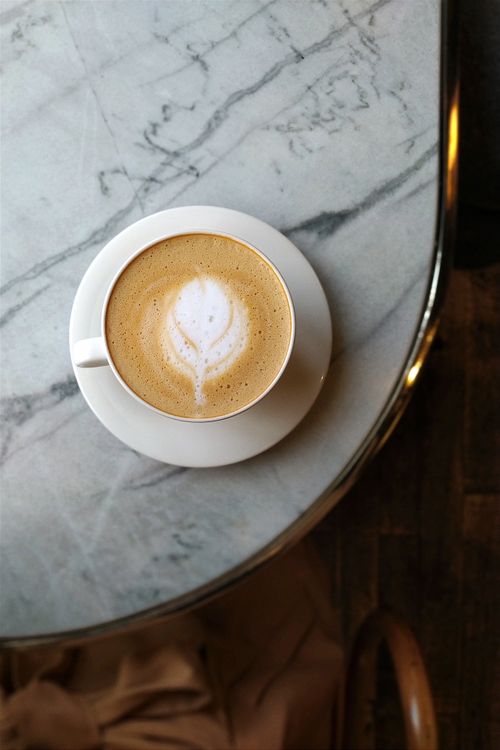 Free Top view of a latte with art on a marble table in a cozy café setting. Stock Photo