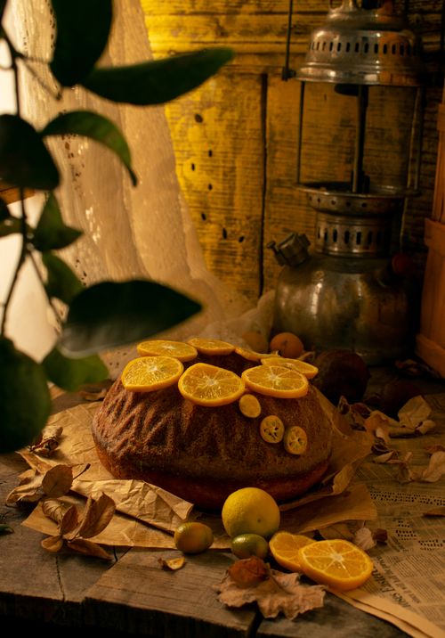 Free A delicious rustic bundt cake topped with orange slices, set in a warm, cozy environment with vintage decor. Stock Photo