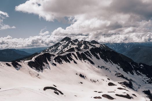 Stunning aerial shot of snow-covered mountain peaks under a partly cloudy sky.