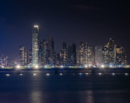 Dramatic night view of Panama City skyline with illuminated skyscrapers reflected on the water.