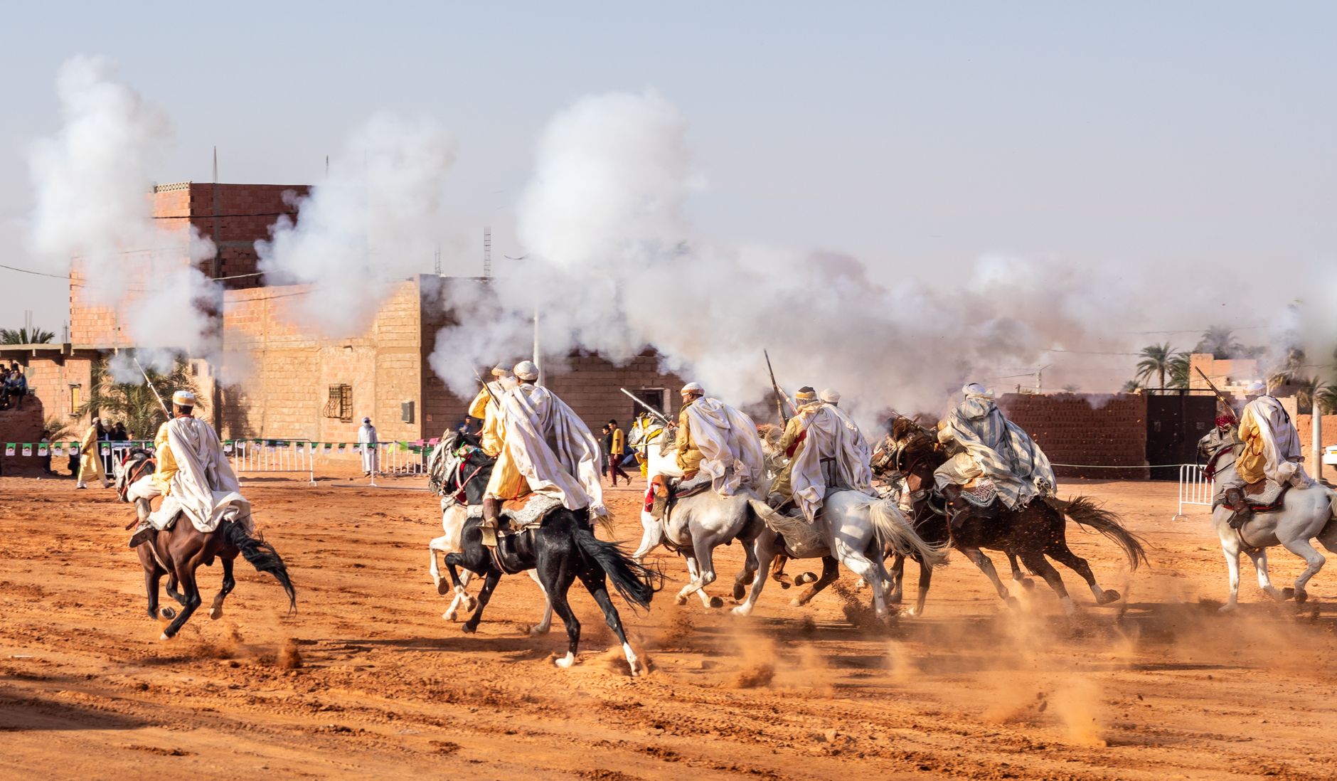 Dramatic scene of Algerian horsemen performing at a traditional festival.