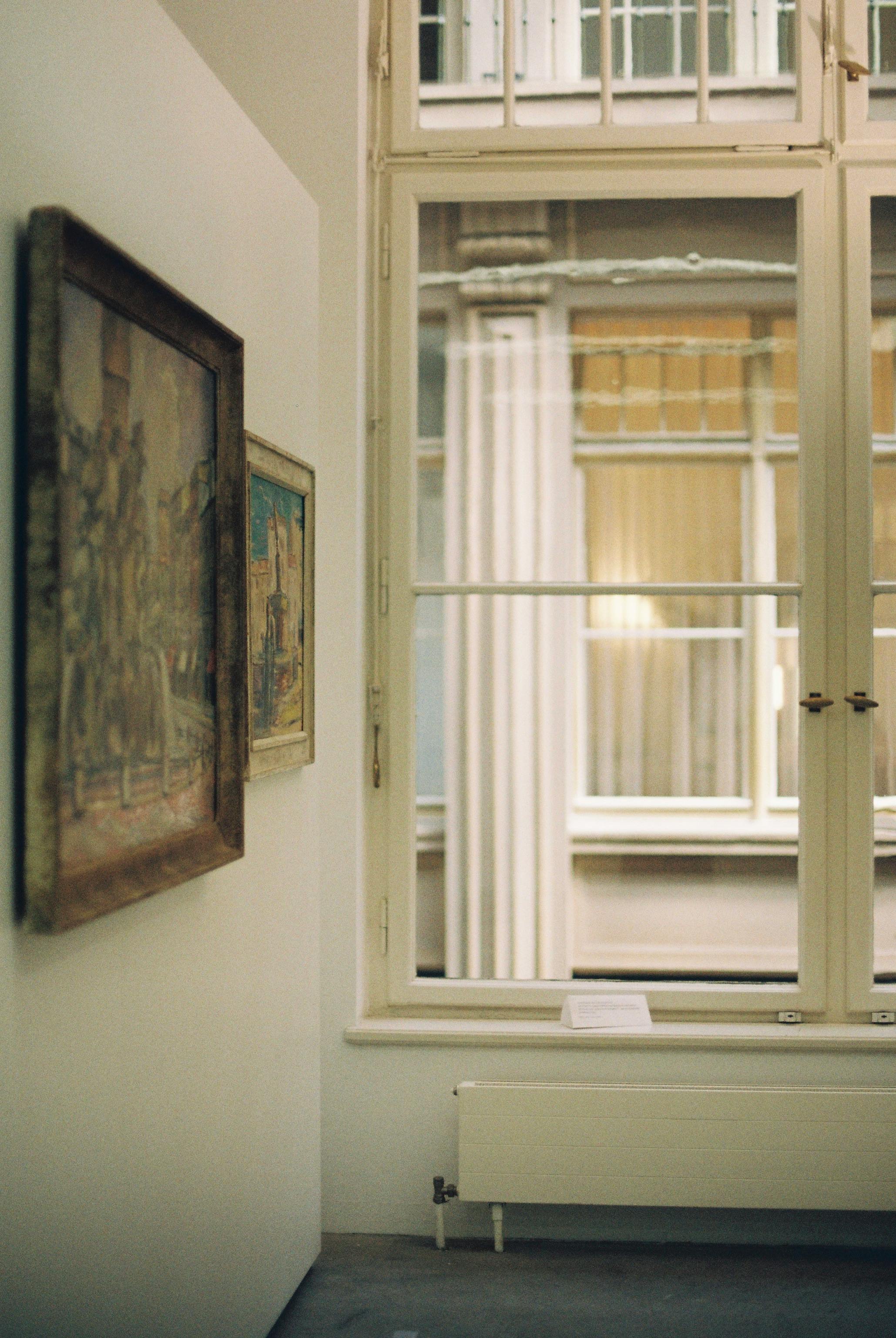 Elegant art gallery interior with framed artworks and large window view.