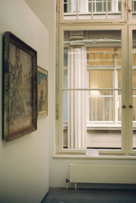 Elegant art gallery interior with framed artworks and large window view.