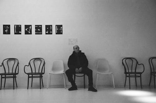 Grayscale Photo of a Man Sitting on Chair