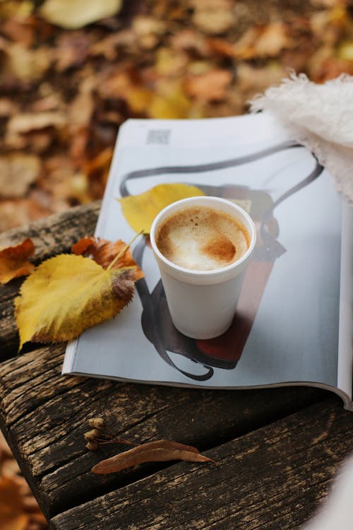 A Cup of Coffee on a Wooden Table Near the Leaves