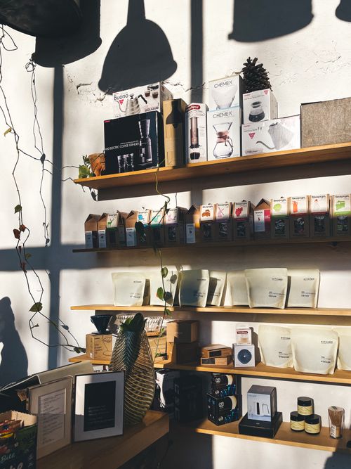 Free Sunlit shelves with various coffee and tea products, creating a cozy retail display. Stock Photo