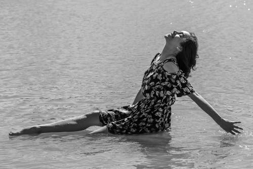 A Grayscale Photo of a Woman Sitting on the Beach