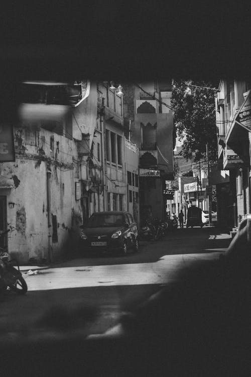 Grayscale Photography of Car and Motorcycle Beside Building