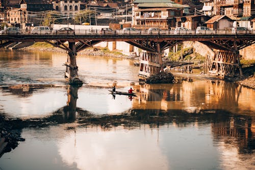 People Riding on Boat on River Under Bridge