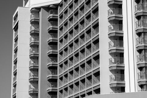 Free A detailed black and white image featuring a high-rise building with numerous balconies. Stock Photo