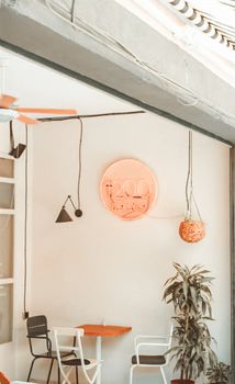 Warm cafe interior with neon sign, orange tones, modern seating, and plant decor.