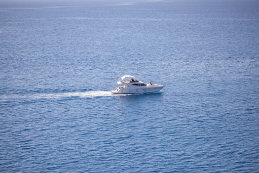 A high-angle view of a luxurious yacht cruising through the calm blue ocean waters.
