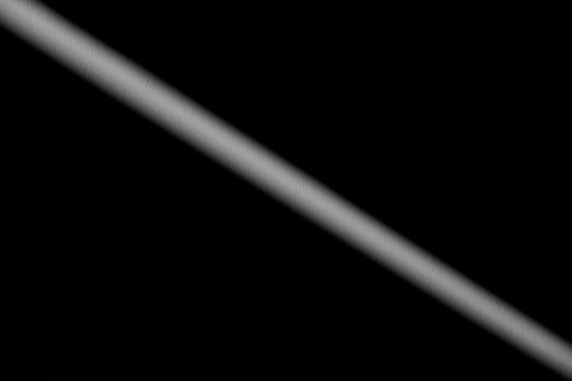 Minimalist image featuring a diagonal shadow across a dark background conveying mystery and simplicity.
