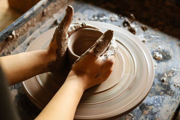 Hands shaping a clay bowl on a potter's wheel — photo by Henlynn on Pexels