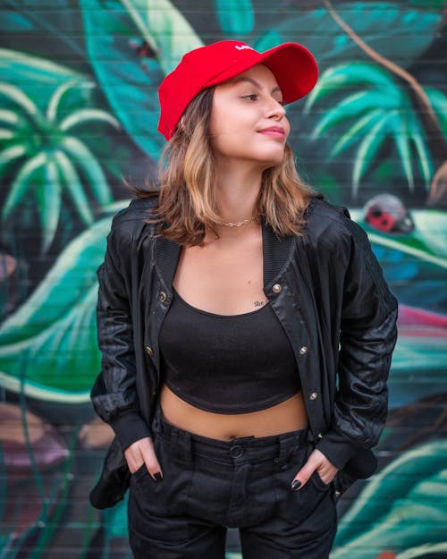 A Woman in Black Jacket Smiling while Wearing Red Cap