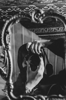 Artistic black and white photo capturing a mirror reflection with a camera.
