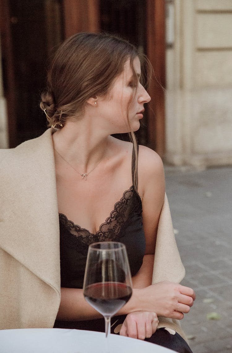 Woman Sitting By Table With Wine