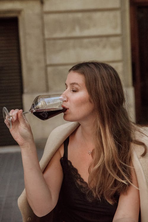 Woman in Black Tank Top Drinking Red Wine