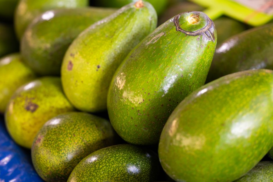Aguacates frescos cortados y enteros sobre superficie de madera, mostrando la pulpa verde clara característica