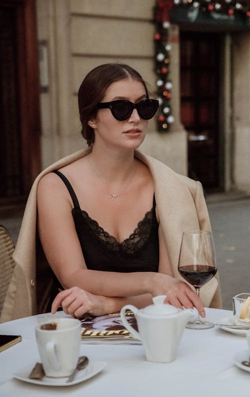 A Beautiful Woman in Black Tank Top Wearing Sunglasses while Holding a Glass of Wine