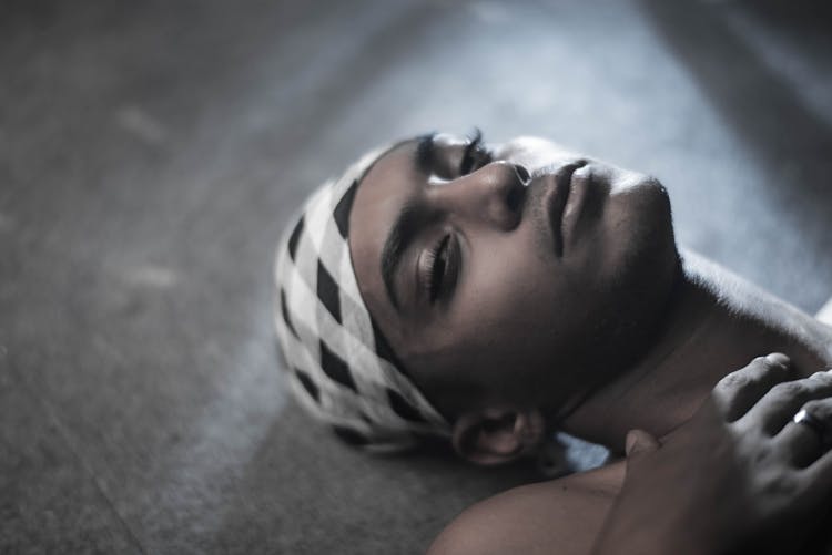 Man Wearing Makeup And Headscarf Lying On Floor
