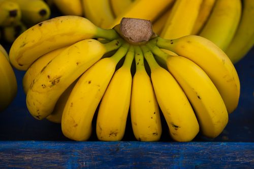 Free Close-up of ripe bananas with vibrant yellow color on a blue background. Stock Photo