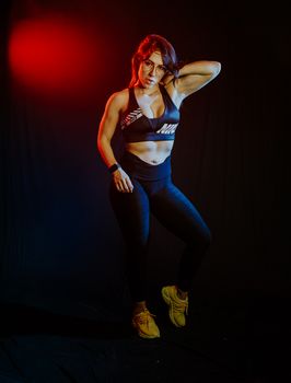 Powerful portrait of woman in active wear with vibrant lighting, showcasing fitness and strength.