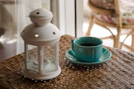 室内氛围宁静，柳条桌上放着一杯碧绿色的咖啡，旁边还点缀着灯笼