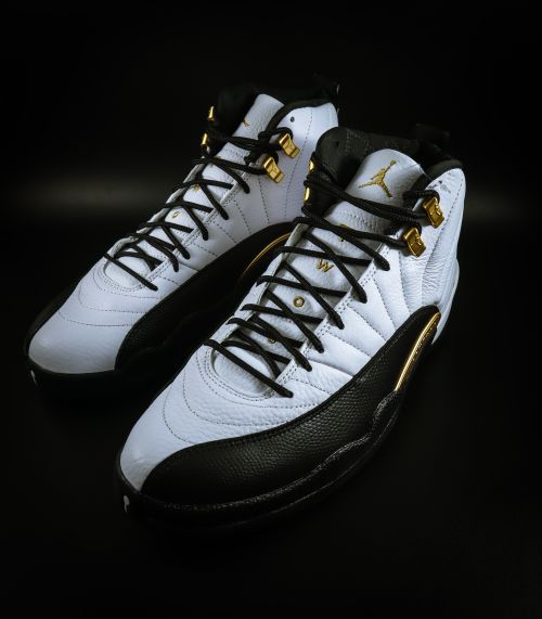 Free Stylish black and white sneakers with gold accents on a dark background, showcasing modern footwear design. Stock Photo