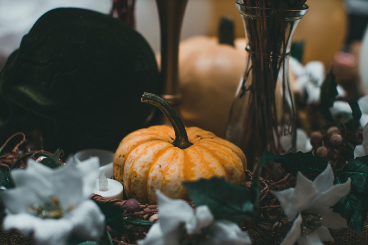 Warm autumnal scene featuring pumpkins, flowers, and candles indoors