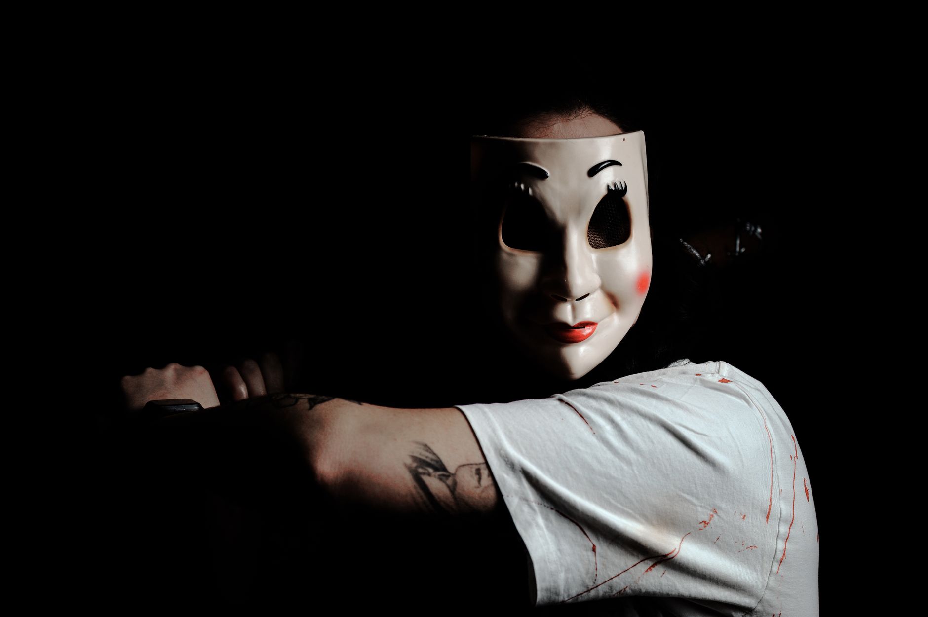 A mysterious figure wearing a mask creates a chilling atmosphere on a dark background.