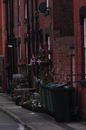 Green Trash Bin Beside Brown Brick Wall