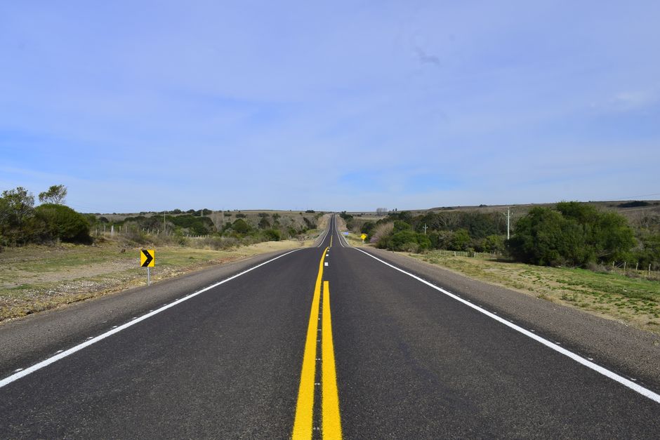 An empty road stretches through Guichon, Uruguay, under a blue sky.