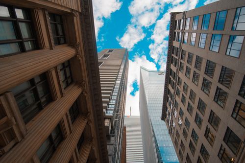 Free Low angle view of modern skyscrapers against blue sky with clouds, showcasing urban architecture. Stock Photo