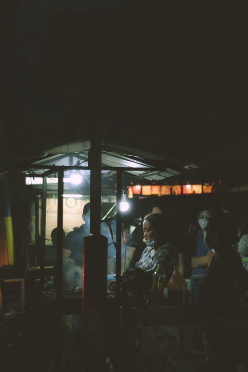 Free A busy night street food stall with people wearing masks and grilling food, showcasing the new normal. Stock Photo